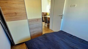 A bedroom with a bed, wooden flooring, a wardrobe, and an air conditioning unit. - Apartment Jelena, modern new, 200m to the beach, free of charge. W-LAN and parking (Vir)