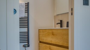 A modern bathroom with a wooden vanity, a towel rack, a mirror, and a toilet. - UrbanFlat 219 - Aura Plage 08 - Aquamoon (Roquebrune-sur-Argens)