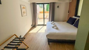Un dormitorio con cama, piso de madera, ventana con cortinas y vistas al exterior.