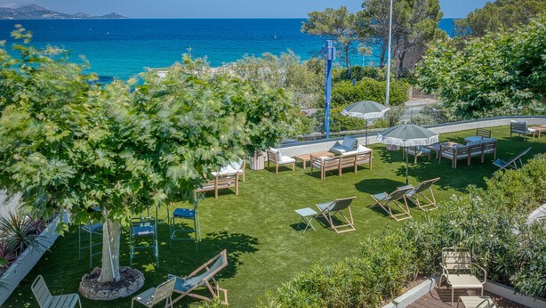 Un patio con mobiliario exterior, vista al mar y un césped cuidado.