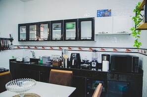 A kitchen with a black countertop, a coffee maker, a microwave, and a set of cabinets above the counter. - Casa Pet Friendly em Condom nio c Vaga em Marituba (Marituba)