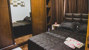 A bedroom with a bed, a nightstand, a mirror, and a wardrobe. - Casa Pet Friendly em Condom nio c Vaga em Marituba (Marituba)