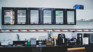 A kitchen with a black countertop, a sink, a coffee maker, and a microwave. - Casa Pet Friendly em Condom nio c Vaga em Marituba (Marituba)