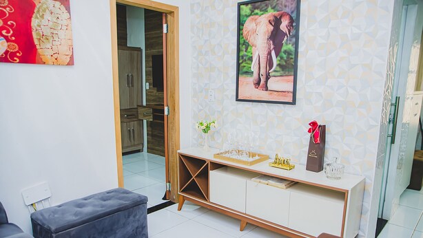 A living room with a sofa, a coffee table, and a cabinet with decorative items. - Casa Pet Friendly em Condom nio c Vaga em Marituba (Marituba)
