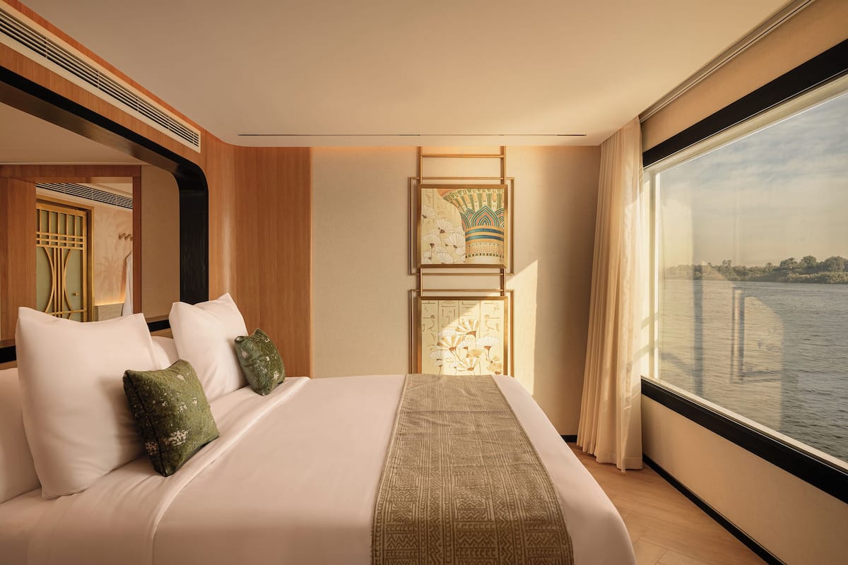 Ein Hotelzimmer mit einem großen Bett, Blick auf das Wasser und einer dekorativen Wandverkleidung.