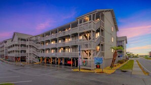 Un hôtel à plusieurs étages doté de balcons extérieurs, d’un parking et d’un panneau indiquant l’emplacement d’une épave.