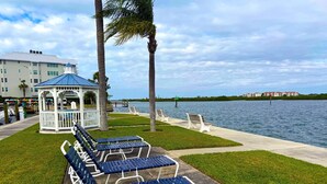 A waterfront park with lounge chairs, a gazebo, and a view of the water. - Sole Retreat 2 Bedroom Condo (Siesta Key)