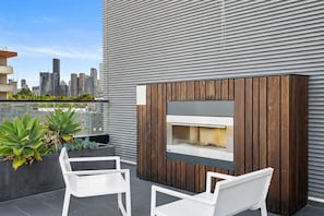 A rooftop terrace with a built-in fireplace, seating area, and potted plants. - The Italian Library: Amazing Views + Free Parking! (Carlton)