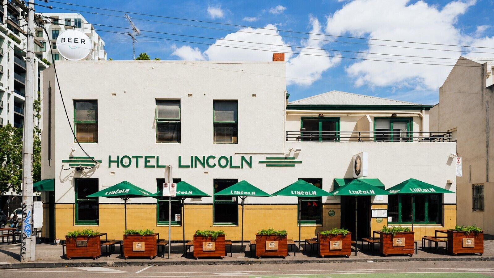 A building with a sign reading 'HOTEL LINCOLN' and multiple green umbrellas.