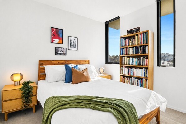 A bedroom with a bed, bedside tables, a bookshelf, and artwork on the wall. - The Italian Library: Amazing Views + Free Parking! (Carlton)