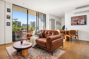 A modern living room with a leather sofa, a round wooden coffee table, and a patterned rug. - The Italian Library: Amazing Views + Free Parking! (Carlton)