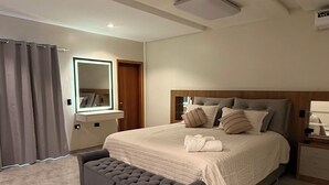 Un dormitorio moderno con una cama grande, una mesita de noche, un espejo y una ventana con cortinas.