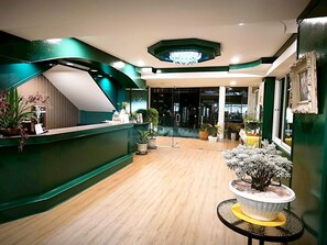 A reception area with a curved green wall, wooden flooring, and potted plants. - Pineapple Residence Pattaya (Pattaya)