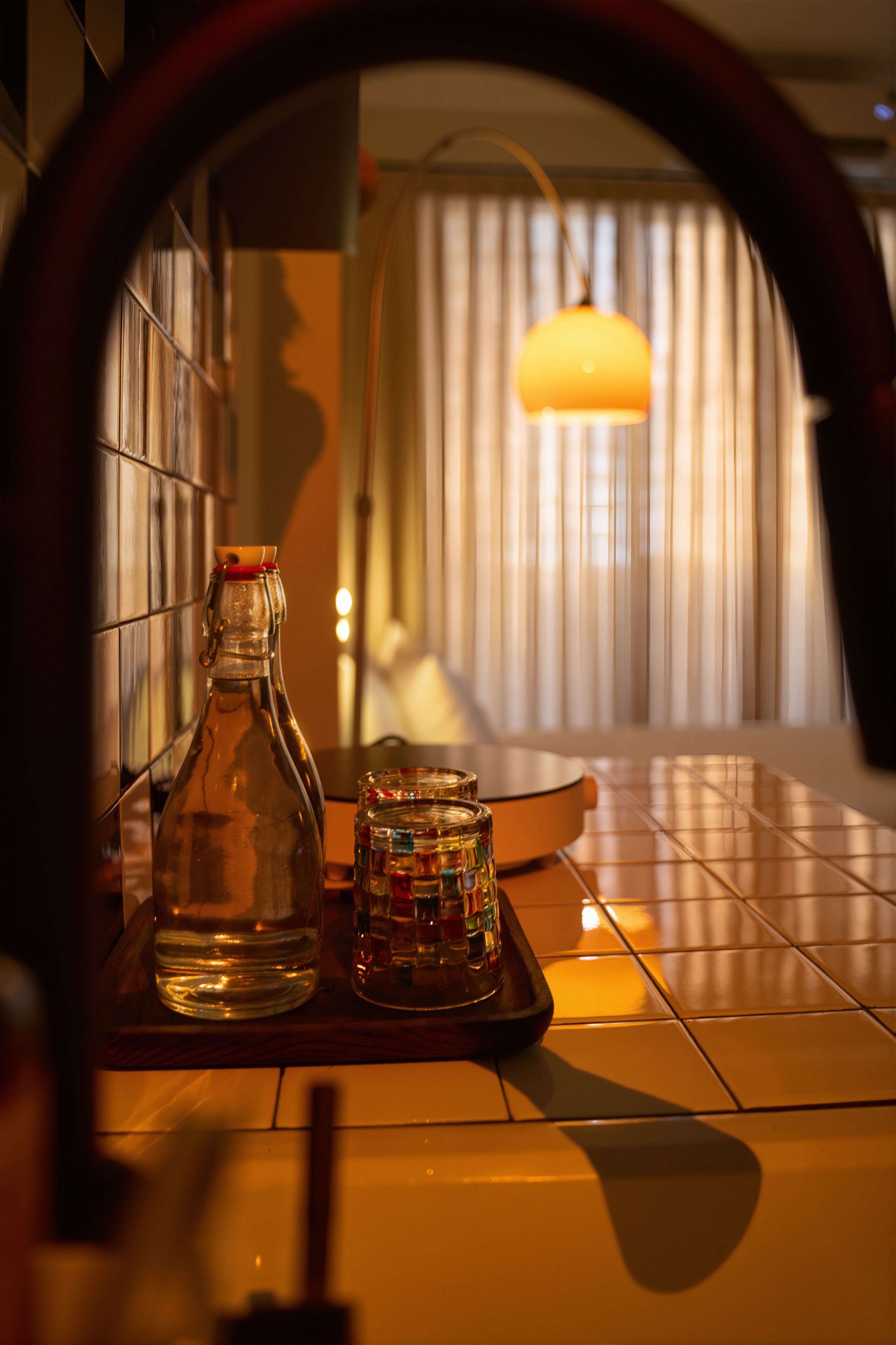 A tiled floor with a bottle and a jar on a tray.