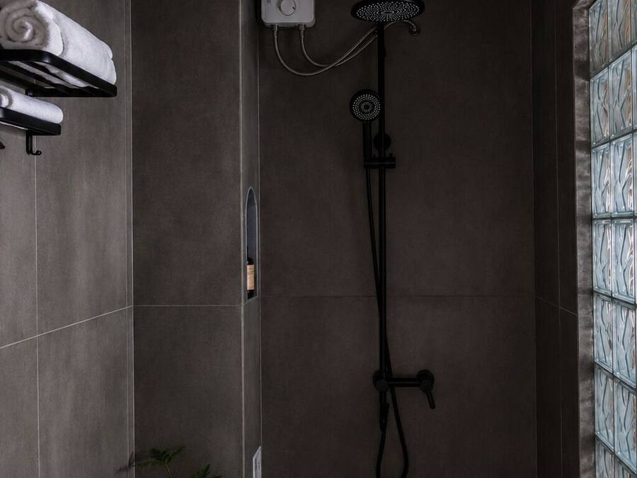 A modern bathroom with a shower, a towel rack, a toilet, and a potted plant.