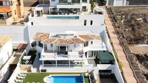 Un edifici residencial de diversos pisos amb una piscina al terrat, balcons i un jardí ben guarnit.