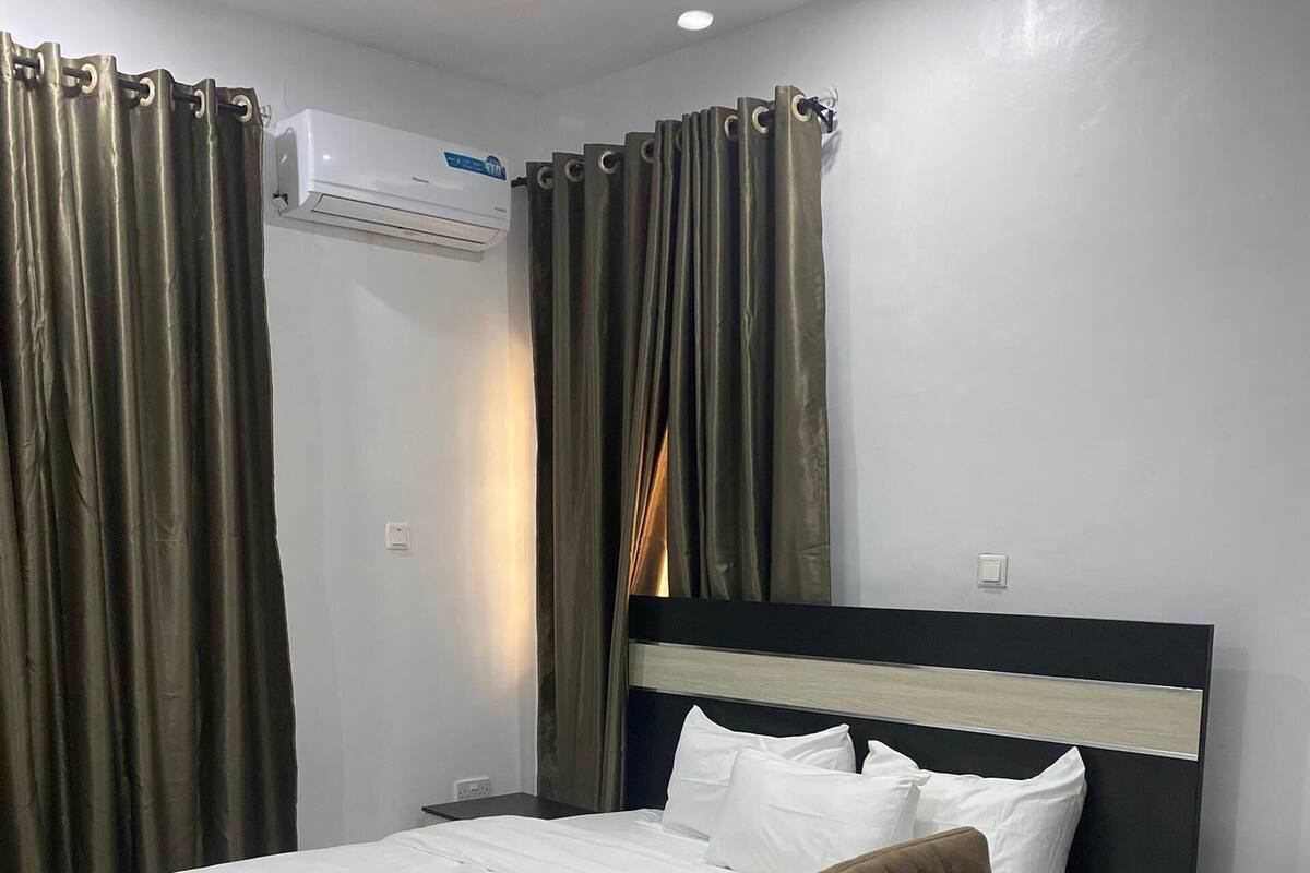 A modern hotel room with a large bed, a desk, and a chair.