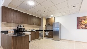 Eine moderne Küche mit Holzschränken, Edelstahlgeräten und Fliesenboden.