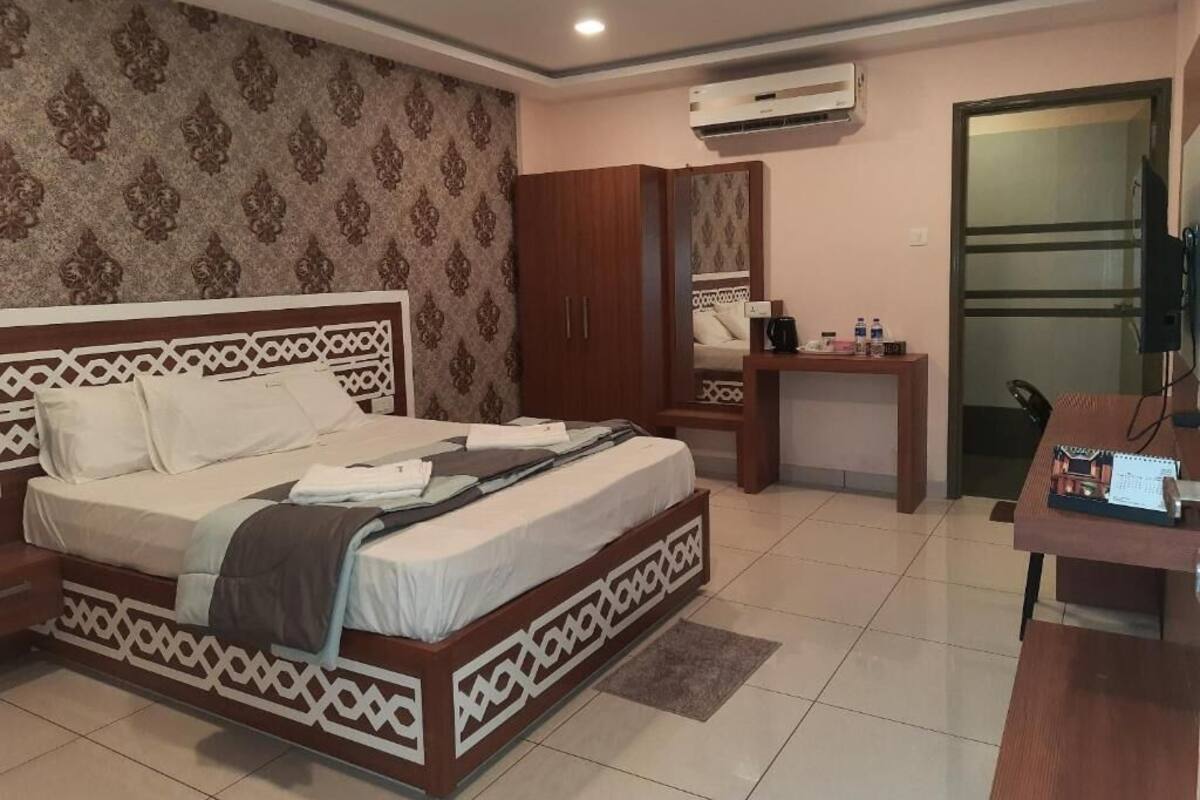 A bedroom with a bed, wardrobe, desk, and air conditioning unit.