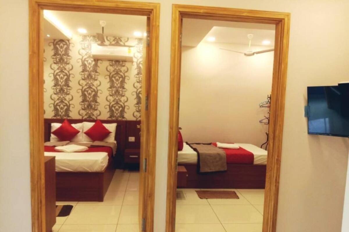 A mirrored room with two beds, a TV, and a ceiling fan.