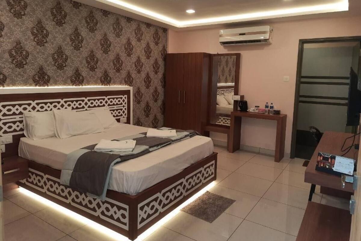 A bedroom with a bed, wardrobe, desk, and air conditioning unit.