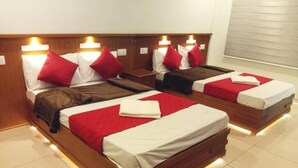 A hotel room with four beds arranged in a row, each with a wooden headboard and red and white bedding. - Emerald Royal Residency (Aluva)