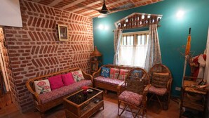 Una sala de estar acogedora con pared de ladrillo, un conjunto de sofá, sillones de mimbre y una mesa de centro.