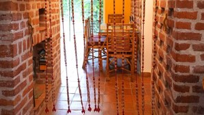 Un estrecho pasillo con paredes de ladrillo, una silla de madera y un adorno colgante.