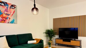 A modern living room with a green sofa, a coffee table, a TV, and a painting on the wall. - Vienna Homey Place - Spacious 70m2 Apartment (vie)
