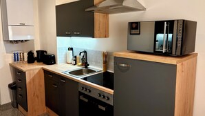 A compact kitchen with a built-in stove, a sink, and a refrigerator. - Vienna Homey Place - Spacious 70m2 Apartment (vie)