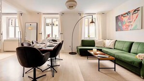 A modern living room with a dining area, a green sofa, and a painting on the wall. - Vienna Homey Place - Spacious 70m2 Apartment (vie)