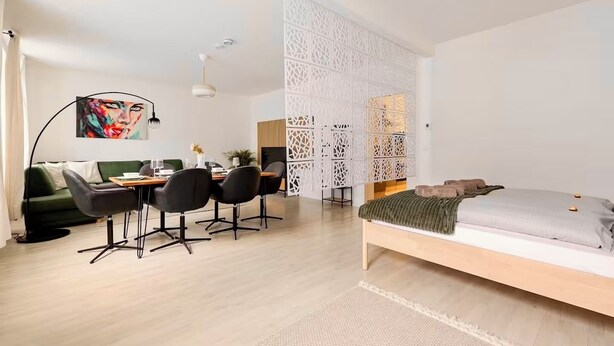 A modern bedroom with a bed, a desk with chairs, a sofa, and a decorative wall panel. - Vienna Homey Place - Spacious 70m2 Apartment (vie)