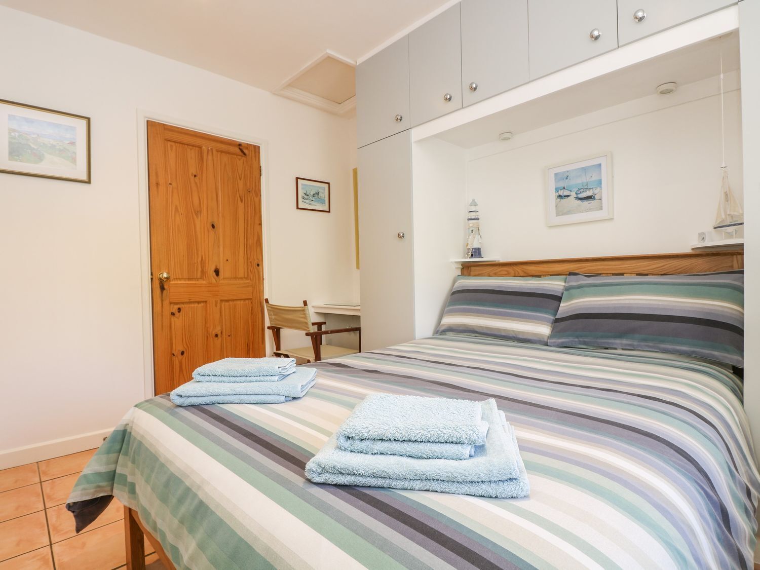 A bedroom with a bed, a wooden door, a desk, and a chair.