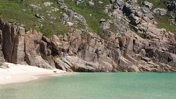 A rocky coastline with clear turquoise waters and a sandy beach.