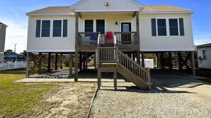 Ein zweistöckiges Haus mit einer Veranda und einer Holztreppe, die zum Deck führt.