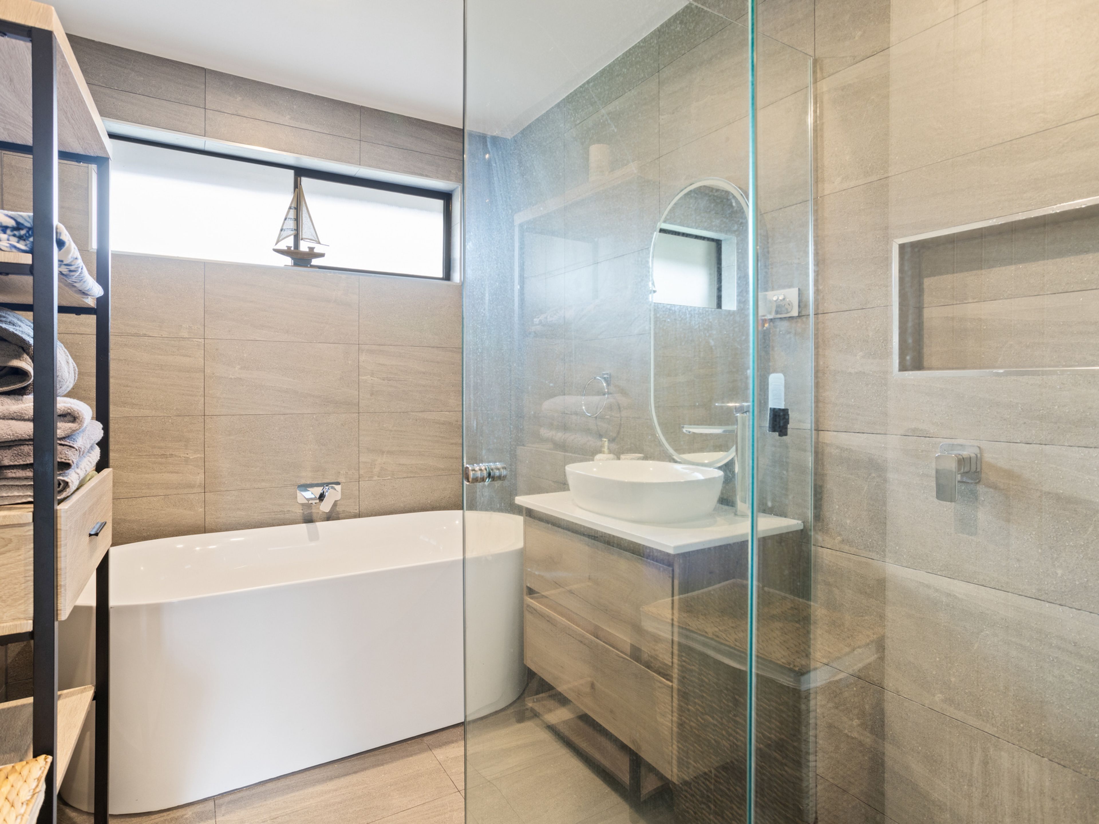 A modern bathroom with a glass-enclosed shower, a freestanding bathtub, and a built-in sink.
