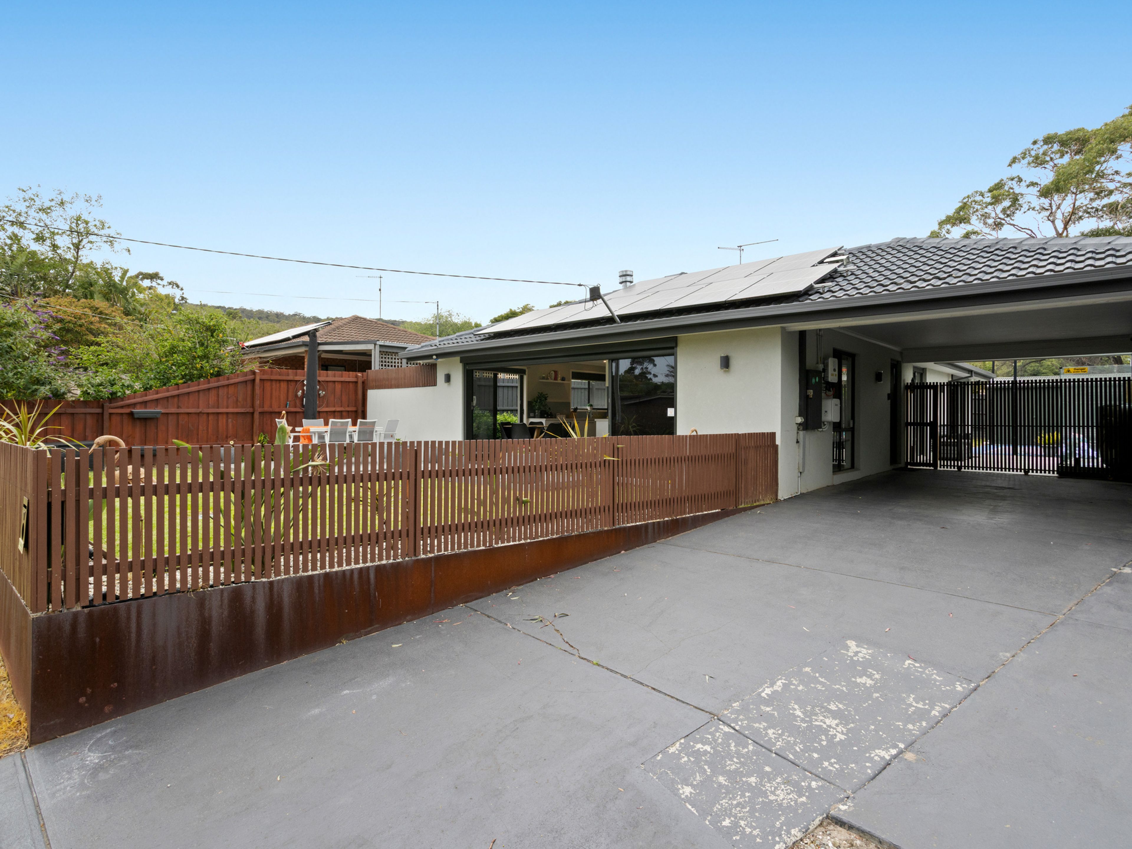 A residential property with a fenced backyard, a garage, and a covered outdoor area.