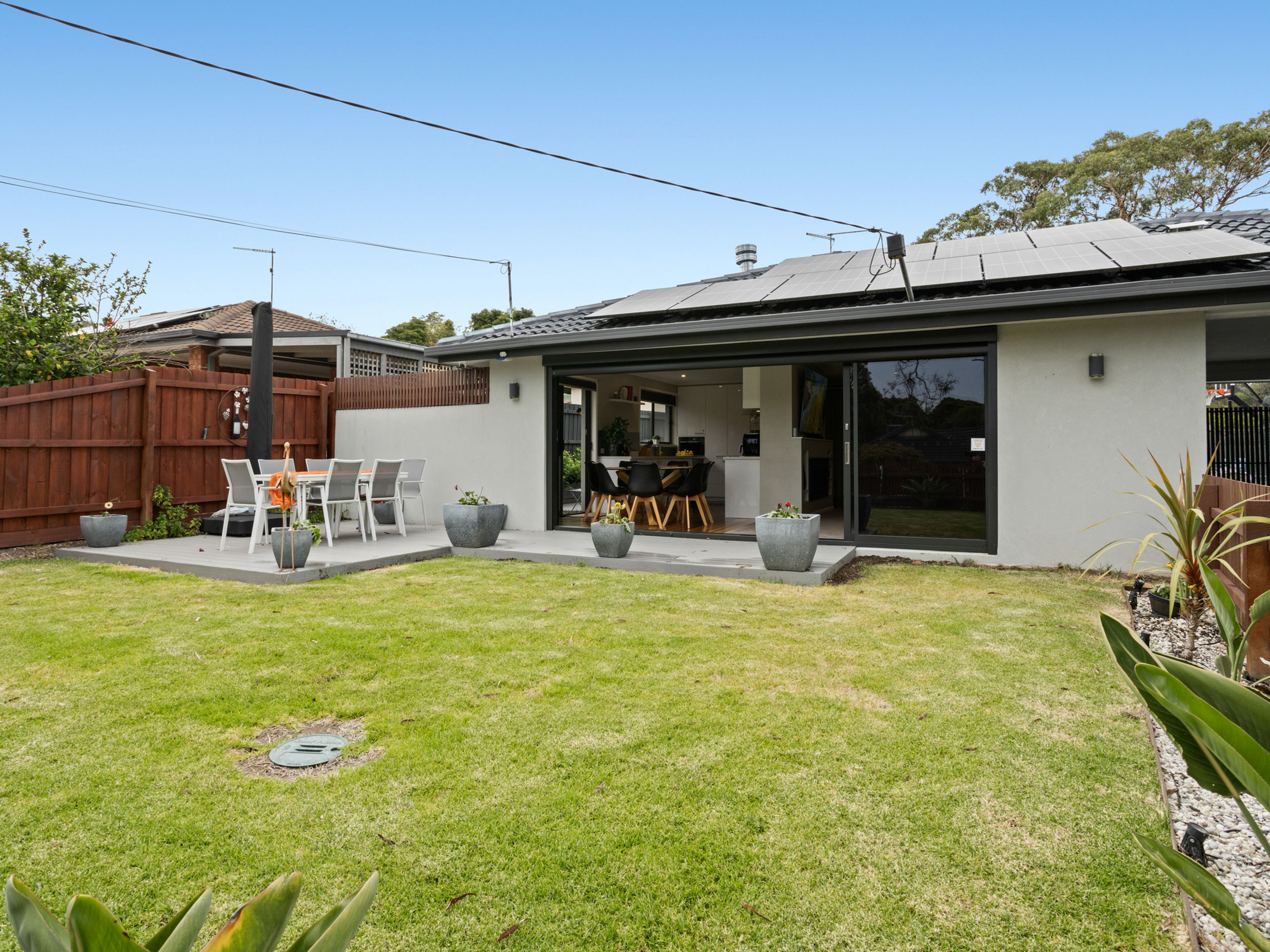 A modern house with a patio, outdoor seating, and a visible kitchen area.