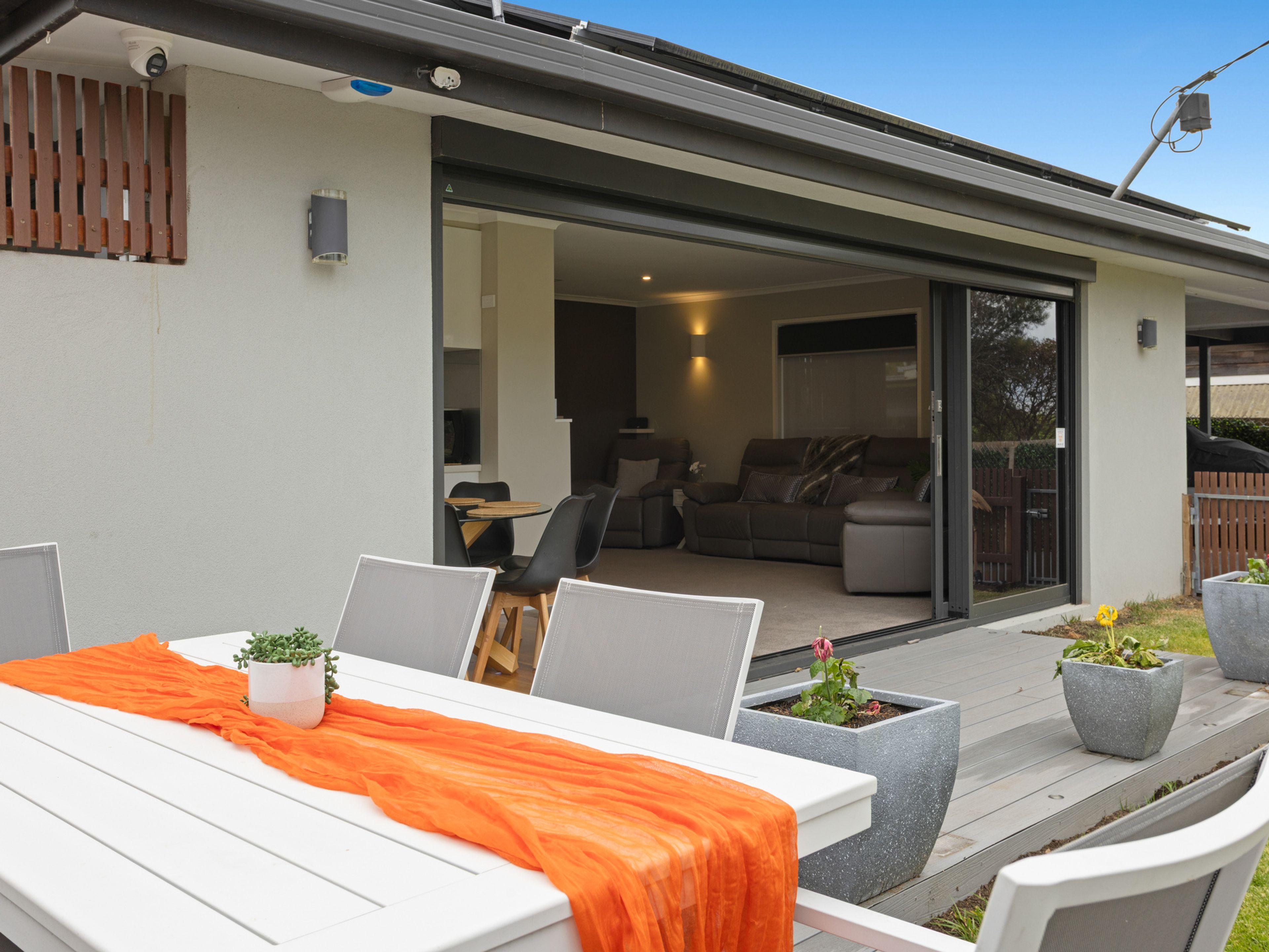 A modern outdoor patio with a dining table, chairs, and potted plants.