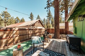 Eine Holzterrasse mit Grill, einem Stuhl und einem kleinen Schuppen.