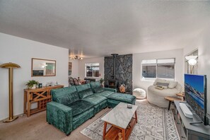 Ein Wohnzimmer mit einem Ecksofa, einem Kamin aus Stein, einem Fernseher und einem Essbereich.