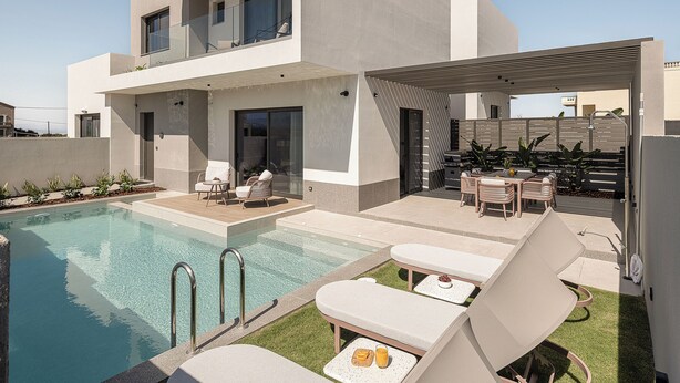Una casa moderna de dos pisos con piscina, zona de estar exterior y terraza cubierta.
