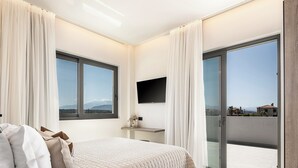 Un dormitorio moderno con una cama grande, un televisor de pantalla plana montado en la pared y un balcón con vistas a la ciudad.