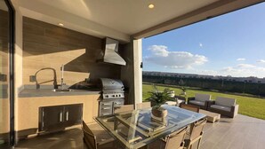 A modern kitchen with a glass dining table, built-in cabinets, and a view of the outdoors. - Brand New Home with 4 En-Suites, near Disney (Kissimmee)