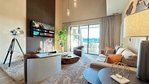 A modern living room with a large flat-screen TV, a sofa, a coffee table, and a lamp. - Brand New Home with 4 En-Suites, near Disney (Kissimmee)