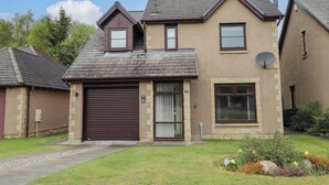 A two-story house with a garage, satellite dish, and a well-maintained lawn. - 6 Carn Dearg (Aviemore)