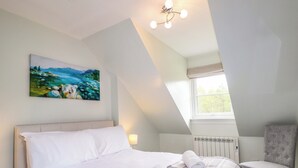 A bedroom with a bed, a painting, a window, a radiator, and a chair. - 6 Carn Dearg (Aviemore)