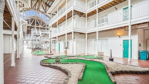 Ein geräumiger Atrium mit mehreren Ebenen, einer zentralen, künstlichen Rasenfläche und einer hohen Decke mit freiliegenden Balken.