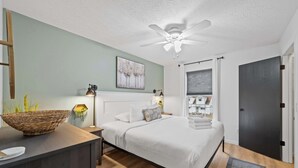 A modern bedroom with a bed, bedside tables, a ceiling fan, and a view of the outside. - Private Parking, Fire Ring, King Beds - Near Ark! (Dry Ridge)