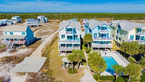 A coastal resort with multiple two-story buildings featuring balconies and a swimming pool. - Beachfront | Pet Friendly | Shared Pool, Elevator (Fort Morgan)